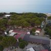 Vista aerea di un campeggio con alberi e bungalow vicino al mare.