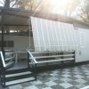 Veranda coperta di una struttura con tenda a righe e sedie di plastica.