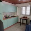 Cucina con mobili verde chiaro, finestre aperte e un piccolo tavolo con sedie.