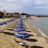 Ombrelloni blu allineati su una spiaggia di sabbia vicino al mare.
