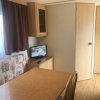 Interno di una stanza con tavolo in legno, televisore su mobile e divano con motivo geometrico.