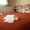 Letto matrimoniale con copriletto arancione e asciugamani bianchi piegati sopra.