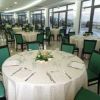 Sala da pranzo con tavoli rotondi apparecchiati e sedie verdi, vista sulle finestre.
