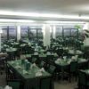 Sala da pranzo ampia con tavoli apparecchiati e sedie verdi.