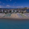 Spiaggia affollata con ombrelloni colorati e mare calmo.