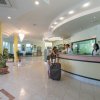 Reception di un hotel con persone al banco e piante decorative intorno.