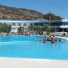 Una grande piscina all'aperto con persone che nuotano e un edificio bianco e blu sullo sfondo.