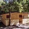 Una piccola casa gialla con veranda, immersa tra gli alberi.