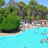 Piscina affollata con persone che nuotano e prendono il sole.