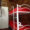 Cameretta con letti a castello rossi e armadio bianco, pareti in legno.