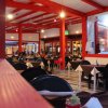 Interno di un ristorante con sedie nere e tavoli apparecchiati, decorato con travi rosse.