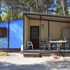 Casetta blu con veranda, sedie bianche e tavolo.