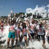 Persone sorridenti in una festa con schiuma all'aperto, tutti bagnati e festosi.