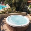 Una vasca idromassaggio rotonda all'aperto, vicina a una piscina e circondata da palme e piante.