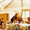 Persone sedute a tavoli con tovaglie bianche sotto grandi ombrelloni in un ristorante all'aperto.