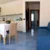Soggiorno con divano blu, tavolo da pranzo e cucina a vista.