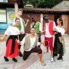 Gruppo di sei persone in costumi tradizionali, alcuni con tamburelli.