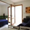 Un soggiorno con divano scuro, tavolo da pranzo e porta finestra che separa la camera da letto.