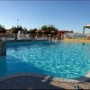 Piscina all'aperto con acqua azzurra, ombrelloni e sdraio.