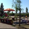 Un parco giochi con biciclette, scivolo e ombrellone arancione.