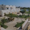 Edificio bianco con giardino, scale e piscina sullo sfondo.