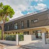 Edificio moderno con rivestimento scuro, circondato da alberi e un cancello.