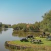 Tavoli da picnic su un prato vicino a un canale circondato da alberi.