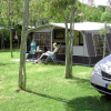 Tenda da campeggio con persona seduta fuori e un'auto parcheggiata.