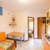 Cucina con divano arancione, tavolo, ingresso di una camera e piano cottura.