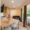 Interno moderno con tavolo da pranzo, cucina e porte finestre aperte su terrazza.