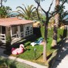 Una casa al mare con giardino, palme, gonfiabile e sdraio. Vista del mare in lontananza.