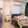 Interno di un bungalow con tavolo apparecchiato, divano a quadri e cucina.