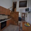 Cucina moderna con mobili in legno, tavolo, scala e TV a muro.