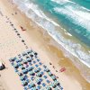 Spiaggia con ombrelloni blu e onde.