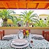 Tavola apparecchiata su terrazza con vista su palme.