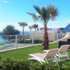 Due lettini bianchi su un prato con vista panoramica sul mare e palme.