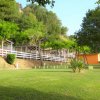 Complesso di bungalow su una collinetta verde, circondato da alberi e ampio prato.
