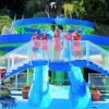 Cinque persone in divisa rossa posano sopra uno scivolo acquatico blu con decorazioni colorate.