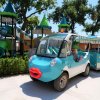 Un'auto elettrica decorata con una faccia felice vicino a un parco giochi con scivoli verdi.