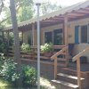 Casa mobile con veranda in legno, circondata da alberi e piante.