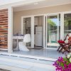 Veranda con tavolino, sedie e fiori colorati davanti a una porta vetrata.