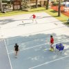 Partita di calcio tennis all'aperto, tre persone giocano su un campo.