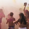 Un gruppo di persone danza tra polveri colorate.