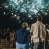 Persone guardano fuochi d'artificio colorati di notte.