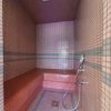 Interno di un bagno turco con piastrelle rosse e blu, doccia a mano e sedile integrato.