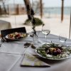 Tavolo apparecchiato all'aperto con piatti e bicchieri di vino.