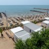 Spiaggia con ombrelloni e passerella verso il mare.