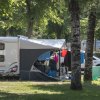 Una roulotte con tenda montata in un campeggio tra alberi.