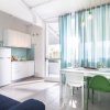 Cucina moderna con tavolo bianco, sedie colorate e tende a righe blu.
