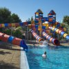 Acquascivoli colorati conducono a una piscina all'aperto con persone che si divertono.